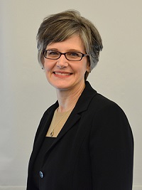 A portrait of a woman wearing glasses and a black jacket